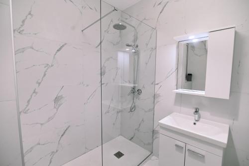 a white bathroom with a shower and a sink at Bright 2 Bedroom flat in Sliema! in Sliema