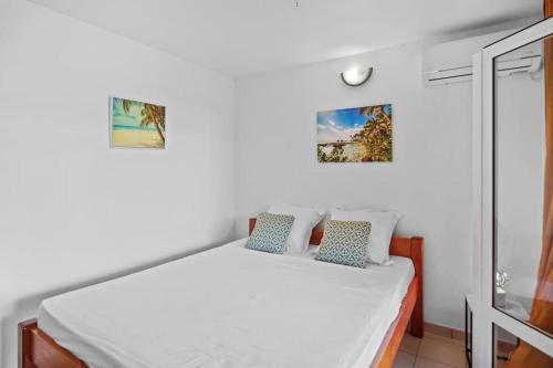 a bedroom with a white bed with blue pillows at Villa Olive O in Le Robert