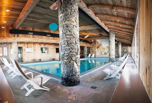 une piscine avec des chaises longues dans un immeuble dans l'établissement Résidence Les Hauts Bois - maeva Home - Appartement 4 pièces 8 personnes Sélection MAE-9753, à Aime La Plagne