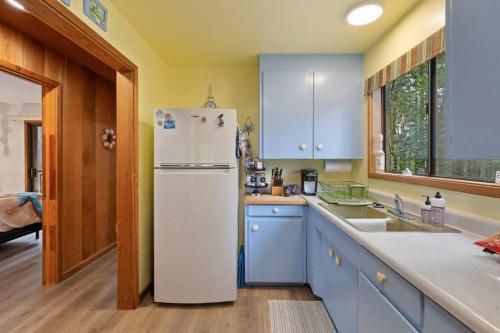 a kitchen with a white refrigerator and blue cabinets at Grandma's Cabin by the Sea in Gualala