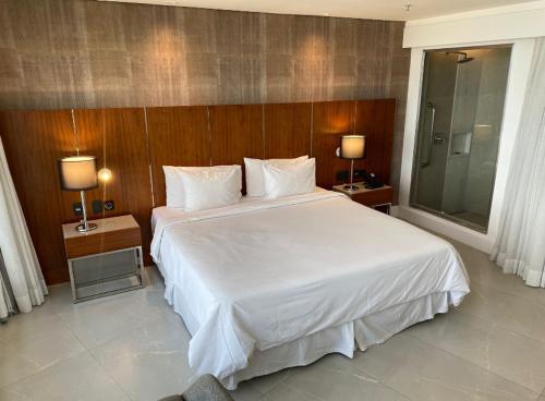 een slaapkamer met een groot wit bed en 2 lampen bij Apart Hotel in Rio de Janeiro