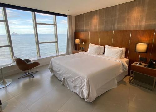 um quarto com uma cama, uma cadeira e janelas em Apart Hotel no Rio de Janeiro