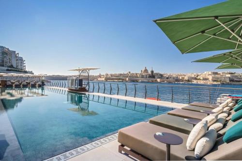 a swimming pool with chaise lounges and chairs at Bright 2 Bedroom flat in Sliema! in Sliema
