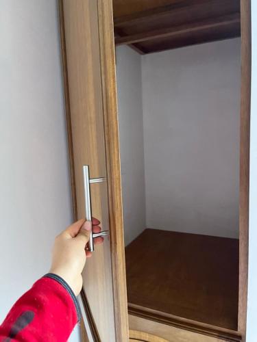 a person opening a wooden door with a handle at CASA FAMILIAR in Huaraz