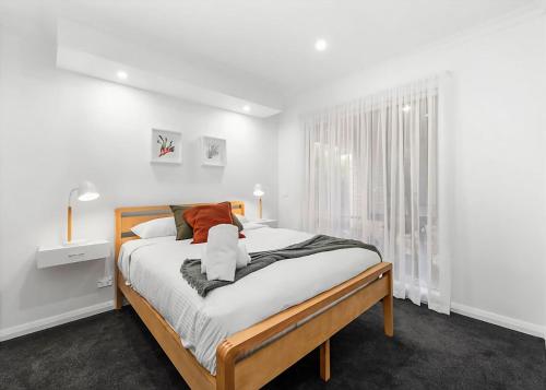 a white bedroom with a bed and a window at Blissful Bungalow Batemans Bay managed by Batemans Bay Accom in Batemans Bay
