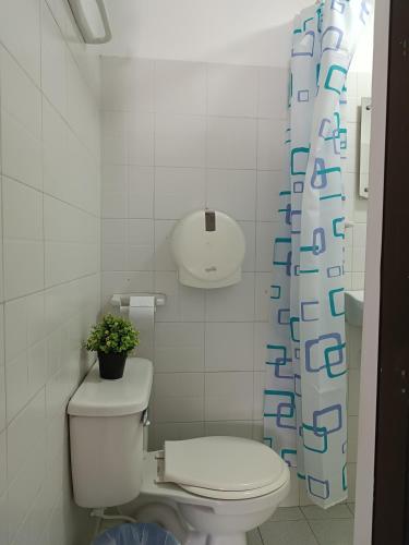 a bathroom with a toilet and a shower curtain at Riviera Central Hotel - Monteria in Montería