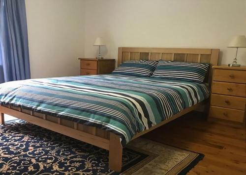 DurrasにあるCarr Street Murramurang National Park managed by Batemans Bay Accomのベッドルーム1室(ストライプ掛け布団付きのベッド1台付)