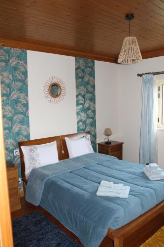 Un dormitorio con una cama azul con toallas. en Casa das Laranjeiras en Alqueidão da Serra