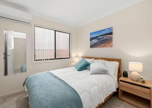 a white bedroom with a bed and a window at Golfers Dream in Batemans Bay