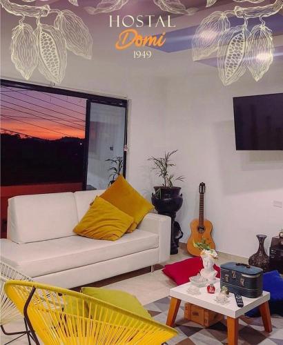 sala de estar con sofá blanco y guitarra en Hostal Domi1949, en San Vicente de Chucurí