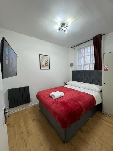 a bedroom with a large bed with a red blanket at Kings Cross-Euston Apartment in London