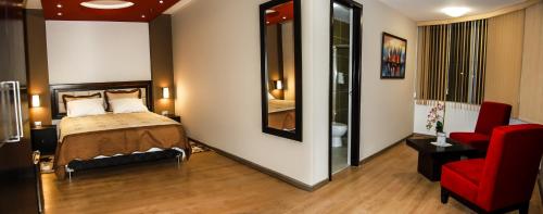 a bedroom with a bed and a red chair at Plaza Sur Hotel & Suites in Tacna
