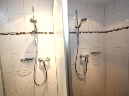 a shower in a bathroom with white tiles at Alpenhaus Lacknerbrunn in Mayrhofen