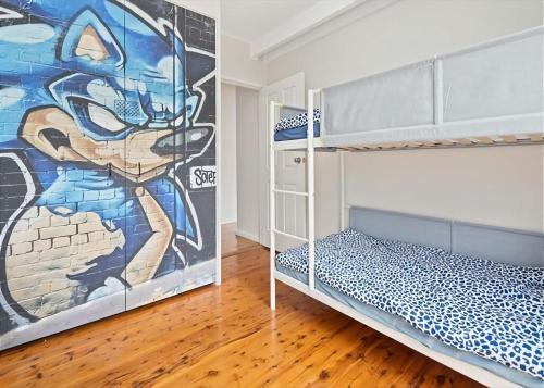 a bedroom with two bunk beds and a mural at Surf Beach Retreat in Surf Beach