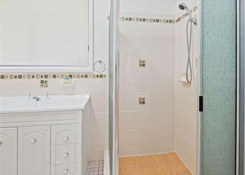 a white bathroom with a shower and a sink at Surf Beach Retreat in Surf Beach
