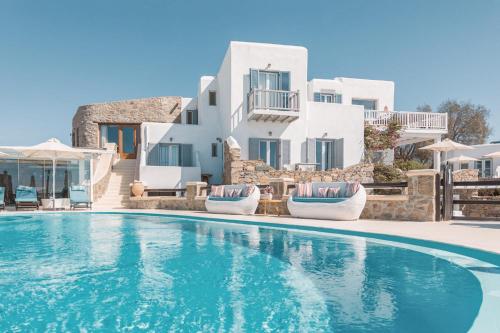 a pool in front of a villa with white buildings at Villa Konstantin Rooms & Suites in Mikonos