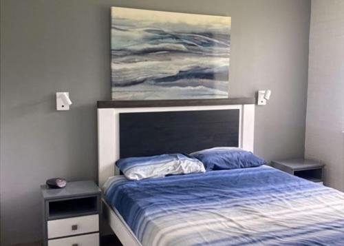 Un dormitorio con una cama con una pintura encima. en Waves at Surf Beach, en Surf Beach