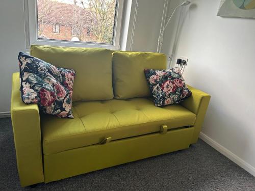 - un canapé jaune avec deux oreillers assis à côté d'une fenêtre dans l'établissement 2 BDR - Entire Flat - Central London, à Londres