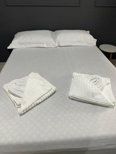 Una cama blanca con dos toallas blancas. en Residencial Paraiso en Sinop
