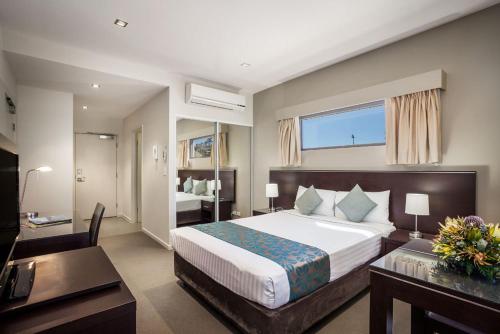 Habitación de hotel con cama grande y escritorio. en Quest Alice Springs, en Alice Springs