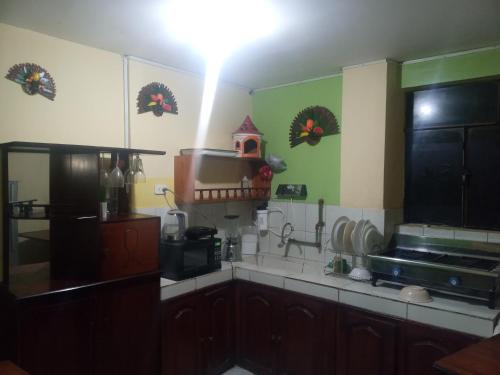 una cocina con armarios de madera y paredes verdes en HOSTAL EL CASTILLO SIGCHOS, en Sigchos