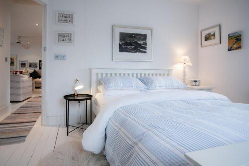 - une chambre blanche avec un grand lit blanc et des oreillers dans l'établissement Ty Y Mor Aberporth, à Aberporth