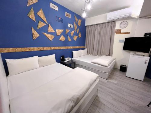 a hotel room with two beds and a blue wall at Inn 逢甲Home in Taichung
