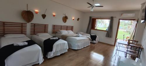 a bedroom with three beds and a window at Pousada Real Cipo in Serra do Cipo