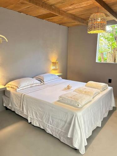 a large white bed in a room with a window at Pousada Odara Caraíva in Porto Seguro