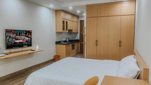 Habitación pequeña con cama blanca y TV. en Yen’s House en Hanói