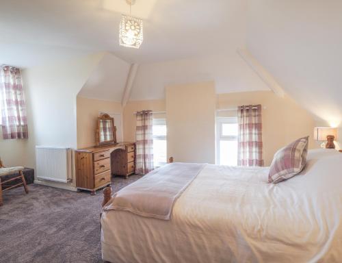 a bedroom with a large white bed and windows at Ferwig New Quay in New Quay