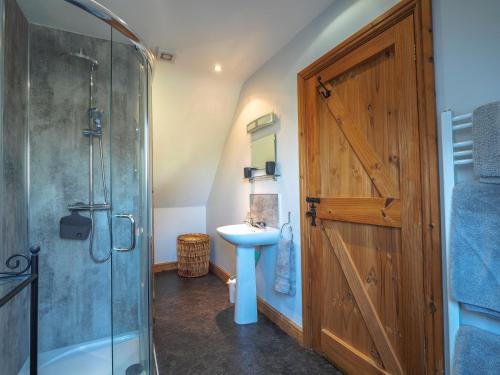 a bathroom with a shower and a sink and a wooden door at Y Beudy Crymych in Whitechurch