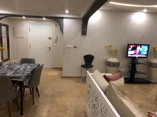 un soggiorno con divano, tavolo e TV di Apartment Majorelle Garden With Pool a Marrakech