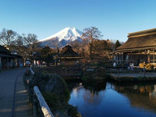 a snow covered mountain in the distance with a river at 福寿苑　Fukujuen in Oshino