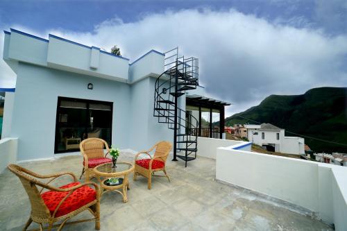 a patio with chairs and a table on a roof at Vrindhavan Mist City Resorts in Kanthalloor
