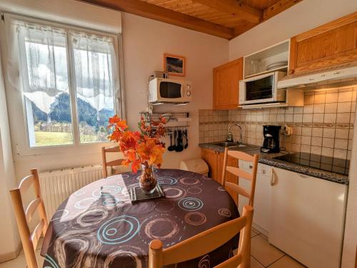 une cuisine avec une table avec un vase de fleurs dessus dans l'établissement Gîte à Gérardmer - Proche lac et pistes, Chem cheminée, 2 chambres - FR-1-589-108, à Gérardmer
