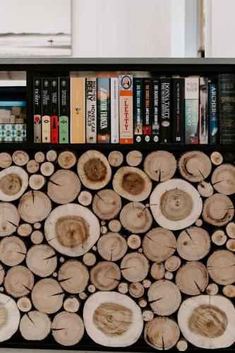 a shelf filled with wooden logs and books at The Endless Summer- 30 seconds walk to the beach in Culburra Beach