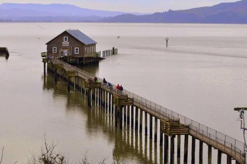 people standing on a dock in a large body of water at Tiki Escape w/ Amazing Mountain and Marsh Backdrop in Rockaway Beach