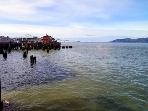 a dock in the water with a red house on it at Tiki Escape w/ Amazing Mountain and Marsh Backdrop in Rockaway Beach