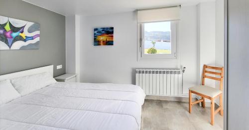 1 dormitorio blanco con 1 cama y 1 silla en AG Casa Vilamar en primera linea de playa Razo, en Razo da Costa
