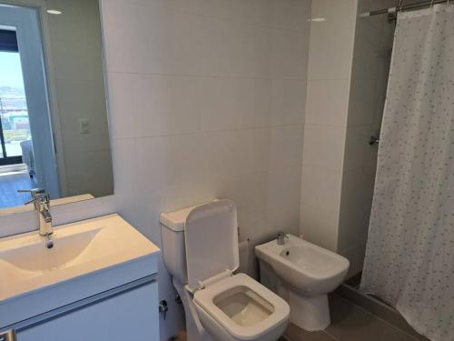 uma casa de banho branca com um WC e um lavatório em 2 dormitorios, parking, gran vista em Montevidéu