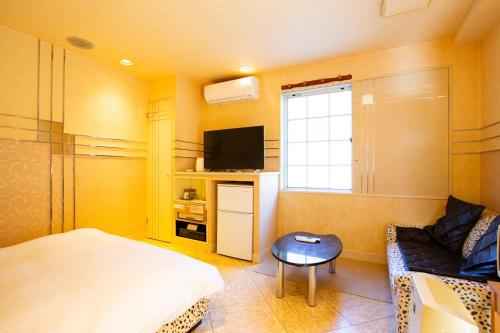 a bedroom with a bed and a tv and a chair at ホテル森のしずく in Shimoda