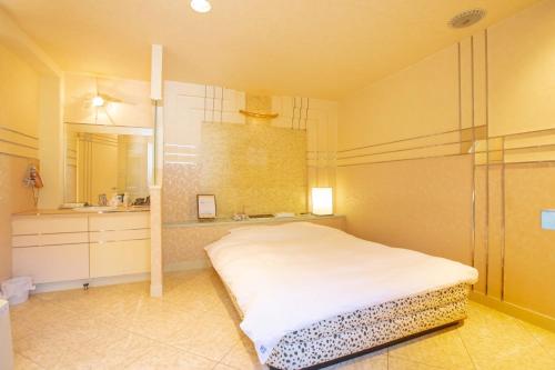 a bedroom with a white bed and a bathroom at ホテル森のしずく in Shimoda