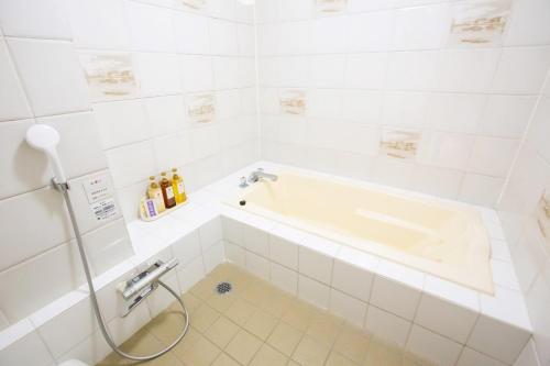 a white bathroom with a tub and a sink at ホテル森のしずく in Shimoda