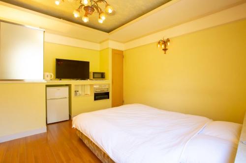 a bedroom with a white bed and a tv at ホテル森のしずく in Shimoda