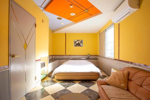 a bedroom with yellow walls and a bed and a couch at ホテル森のしずく in Katsura