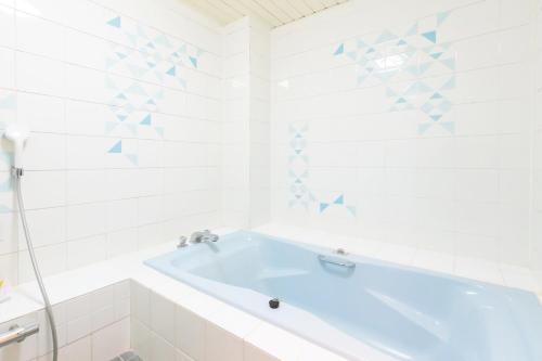 a white bathroom with a blue tub in it at ホテル森のしずく in Katsura