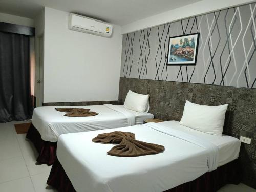 two beds in a hotel room with towels on them at Grand Pruksa Siri Apartment in Sara Buri