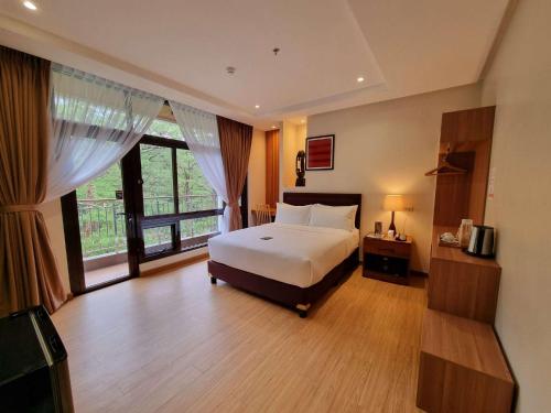 a bedroom with a bed and a large window at Alvea Hotel and Residences in Baguio