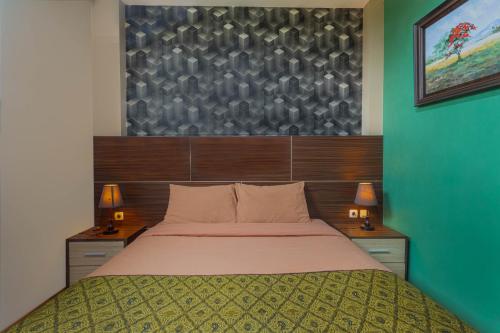 a bedroom with a large bed and two lamps at Hotel DMadinah inn Gentan in Solo